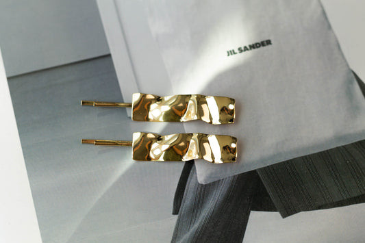 Gold dented rectangle metal hairpins with sculptural texture, displayed on a fashion magazine – modern minimalist hair accessories for sleek everyday styling.