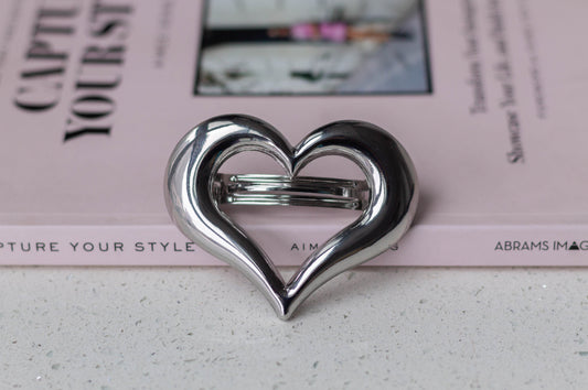 Silver heart-shaped metal hair barrette for women styled on a pink fashion book – romantic hair accessory for everyday wear or special occasions.