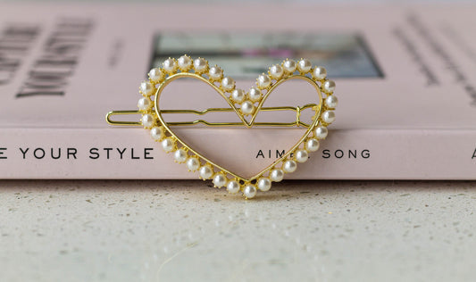 A pearl heart-shaped hairpin placed on a book with the text 'Capture Your Style'.