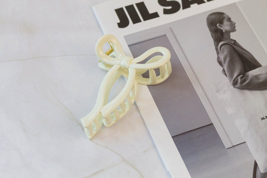 A white hair bow hair claw placed on a magazine.