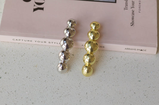 Metal circle barrettes in the colour gold and silver are resting on a pink fashion book.
