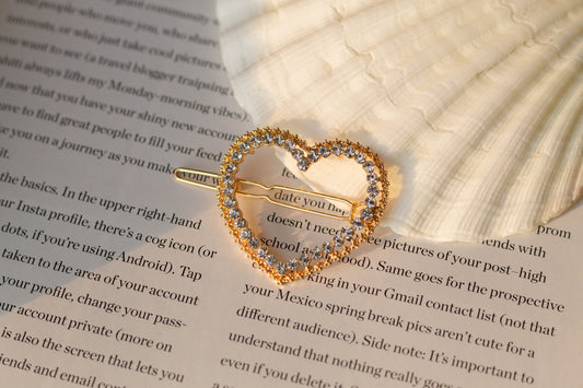 Close-up view of the gold rhinestone star hairpin styled on an open book with a seashell – romantic-inspired accessory for elegant hairstyles.