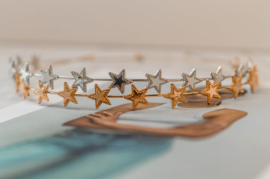 Silver metal headband stacked on top of the gold metal headband with decorative open star accents, elegant celestial hair accessory for special occasions.