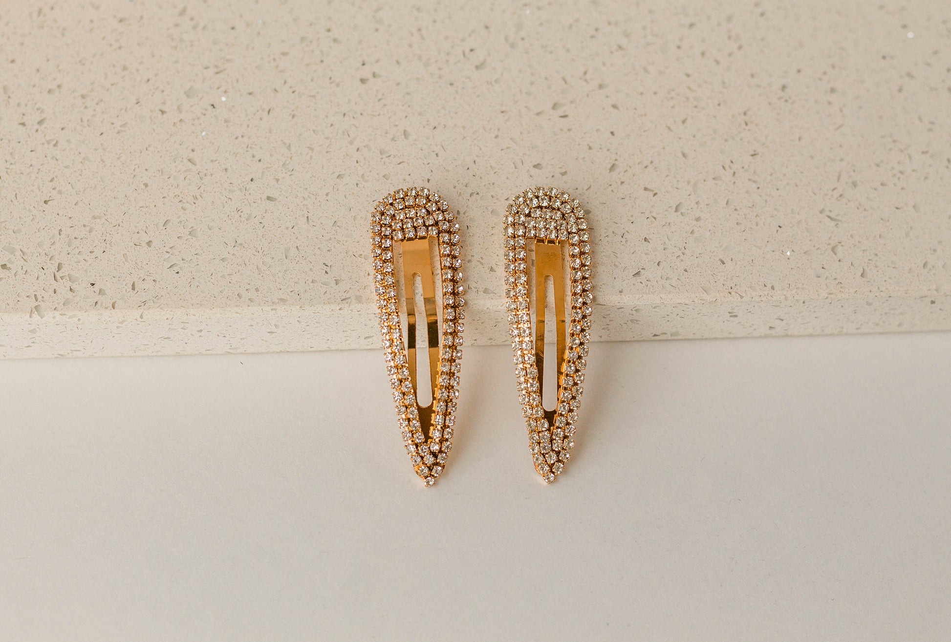 Close-up view of the gold rhinestone hair clips laid against a marble block.