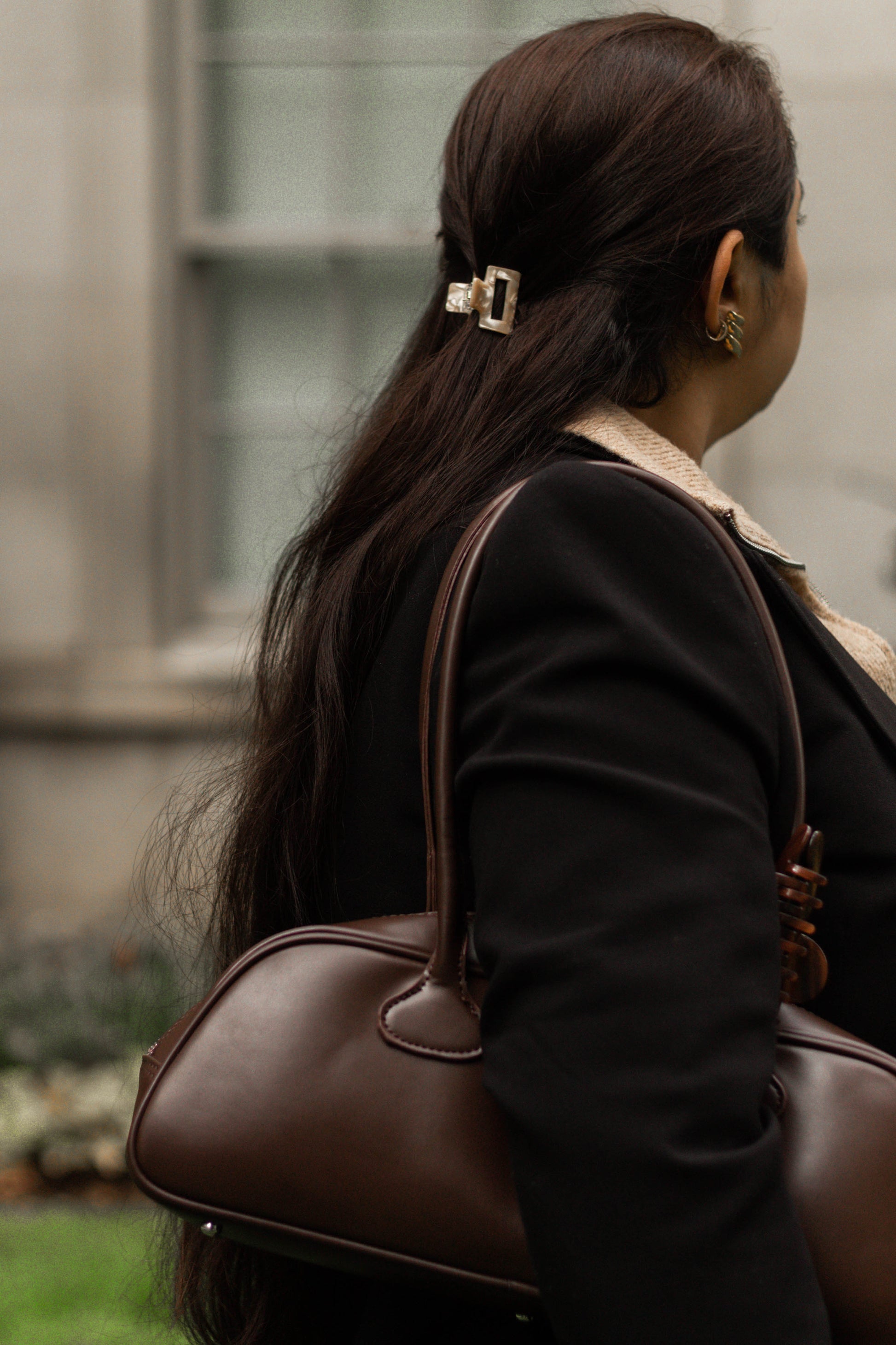 A video showcasing the model in long straight brown hair wearing two mini beige acetate hair claws, styled in a half up-do. 