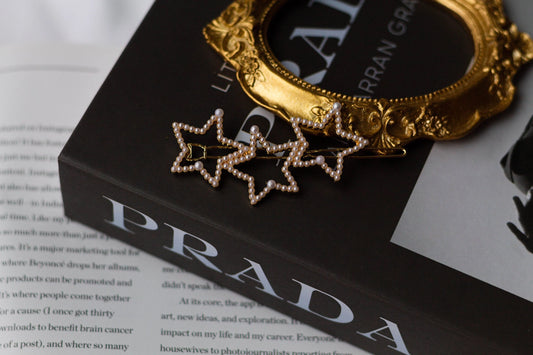 A hairpin with three stars and little pearl details resting on a fashion magazine.